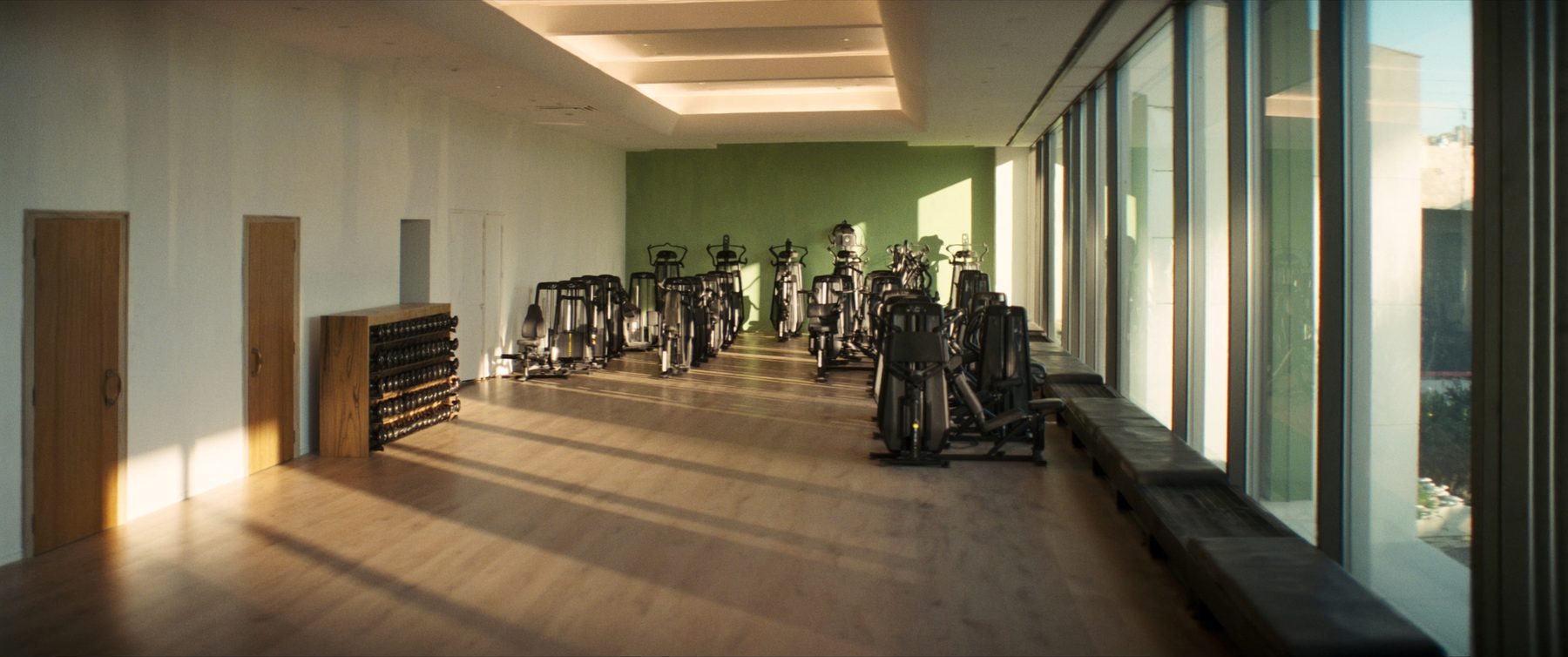 Langer heller Kraftraum mit Fensterfront und zwei Reihen neuer Trainingsgeräte