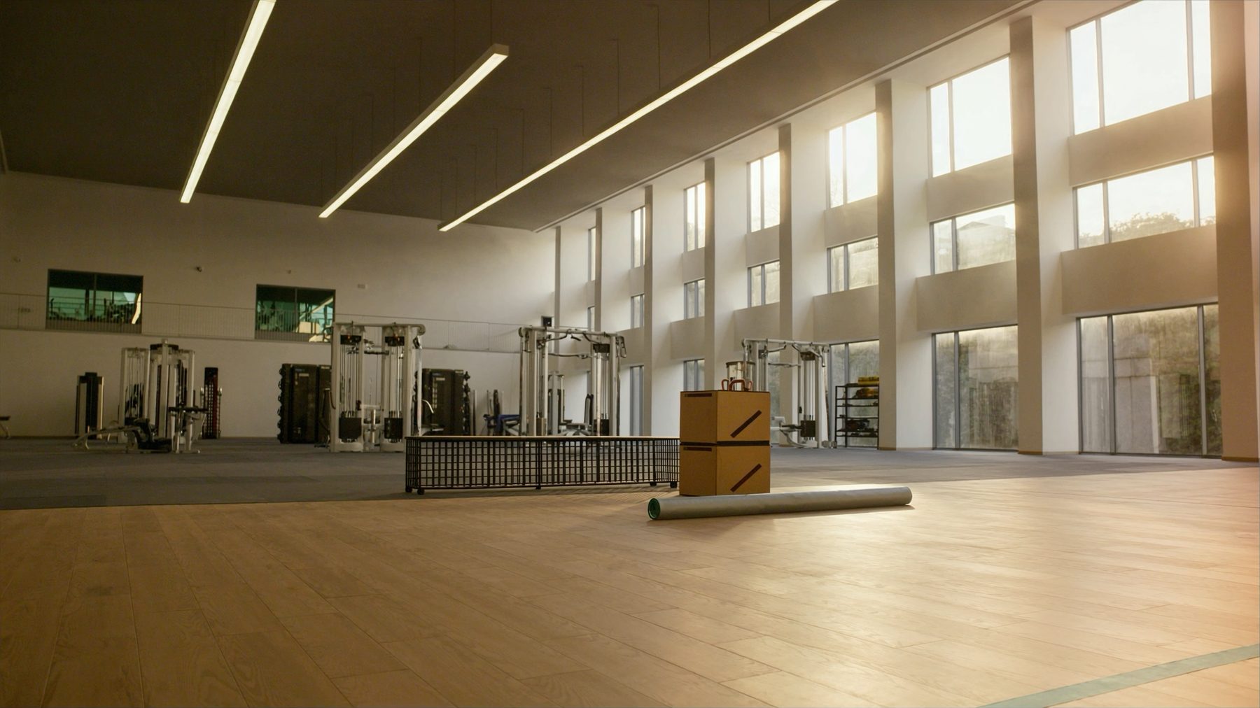 Große helle Trainingshalle mit hoher Decke, Fensterfront und Geräten an der Stirnseite