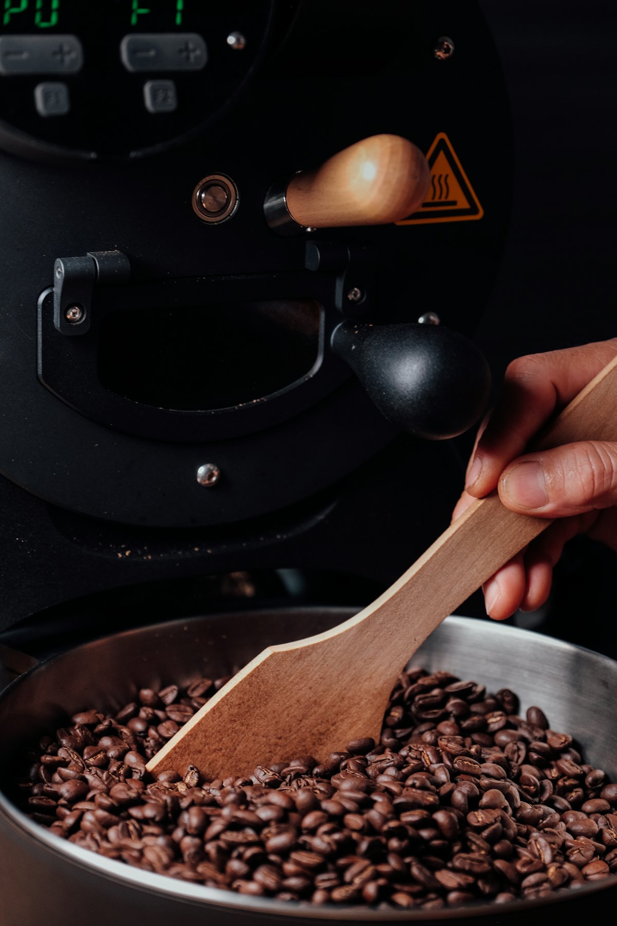 Hand mit Holzlöffel über Kaffeebohnen